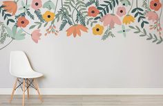 a chair sitting in front of a wall with flowers painted on the walls and leaves hanging from it