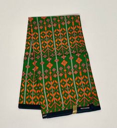 an orange and green patterned cloth on a white surface