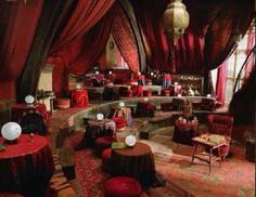 an elaborately decorated room with red drapes and round tables