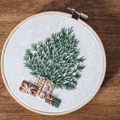 a cross stitch christmas tree with presents in it on a wooden table next to some scissors