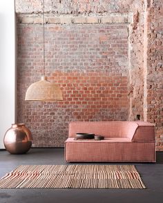 a living room with brick walls and a pink couch in front of a large rug