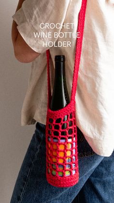 a woman is holding a crochet wine bottle holder in her hands and wearing jeans