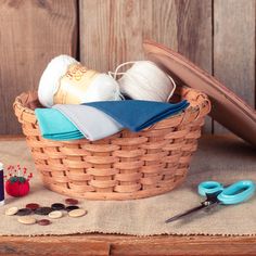 a basket filled with yarn, scissors and other crafting supplies sitting on top of a table