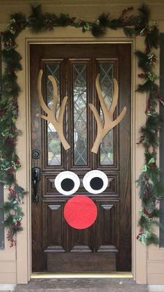 a door decorated with christmas wreaths and reindeer antlers