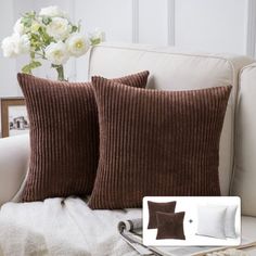 two brown pillows sitting on top of a white couch next to a vase with flowers