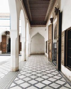 an empty hallway with tiled floors and wooden doors in arabic style architecture at the alhambra palace, marraket, morocco