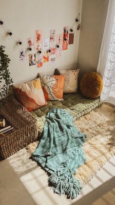 a living room filled with lots of pillows and blankets on top of a floor next to a window