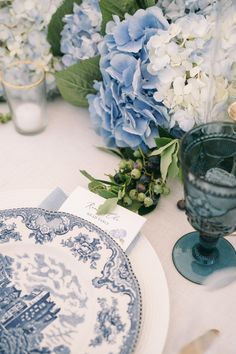 a blue and white table setting with hydrangeas