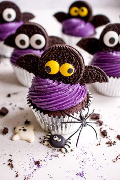 chocolate cupcakes decorated with purple icing and googly eyes are sitting on a white surface