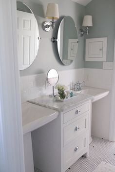 a white bathroom with three mirrors above the sink