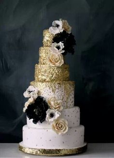 a white and gold wedding cake with flowers on top