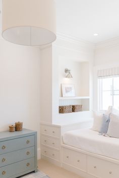 a bedroom with white walls and blue dressers in front of the window, next to a bed