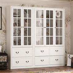 a white china cabinet with glass doors and drawers in a room next to a rug