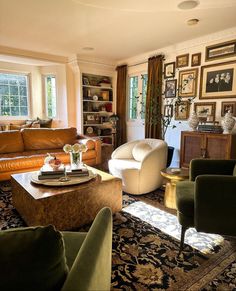 a living room filled with lots of furniture and pictures on the wall above it's windows