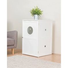 a white cabinet sitting on top of a wooden floor next to a chair and potted plant