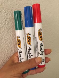 three markers are in the palm of a person's hand while they hold them