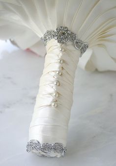 the wedding bouquet is wrapped in white satin and beaded with crystal beads, along with an ornament