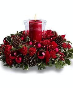 a red candle surrounded by pine cones and poinsettis