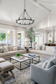 a living room filled with furniture and a chandelier hanging over the top of it