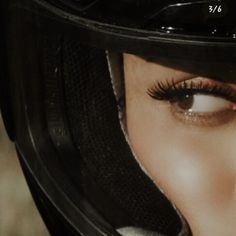 a close up of a woman's face wearing a motorcycle helmet and eyeliners