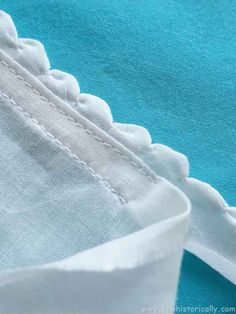 closeup of the stitching on a white and teal colored shirt with ruffles