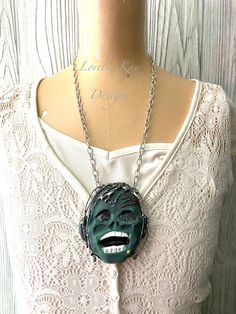 "I created this necklace using a zombie that I hand cast and hand painted. It is sealed so it is very durable for wear. I have given the eyes a glow effect. It is soldered using lead-free solder in my signature style including his hair. It is a nice size at about 3 1/2 x 3 1/4\" . It hangs from a 21\" .999 fine silver plated chain. For more one-of-a-kind creations please click here> http://loreliekaydesigns.etsy.com All designs, images and content copyright ©Lorelie Kay Designs" Unique Handmade Necklaces For Cosplay, Unique Handmade Necklace For Cosplay, Handmade Green Novelty Necklace, Unique Hand Cast Halloween Necklaces, Unique Hand Cast Halloween Necklace, Hand Painted Jewelry For Halloween Gift, Monster Necklace, Witch Doll, Glow Effect