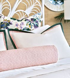 a bed topped with lots of pillows next to a white headboard and wall mounted clock