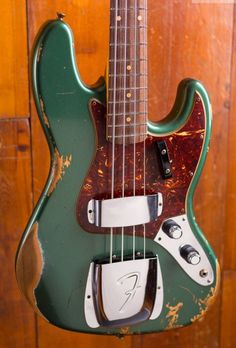 an old green electric guitar hanging on a wooden wall in front of a wood paneled door