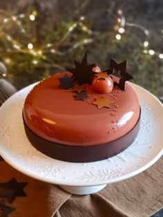 a chocolate cake on a white plate with christmas lights in the background