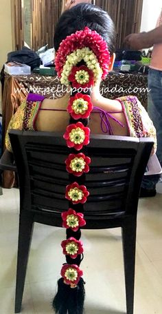 the back of a woman's head with red and green crocheted flowers on it