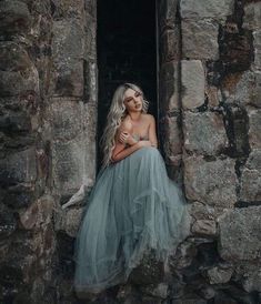 a woman in a blue dress sitting on a window sill