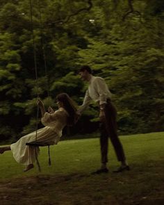 a man and woman on a swing in the park