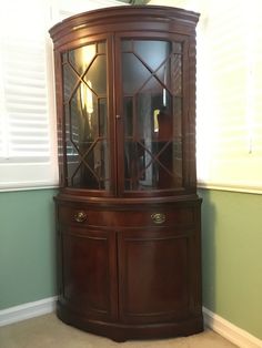 a wooden corner cabinet with glass doors