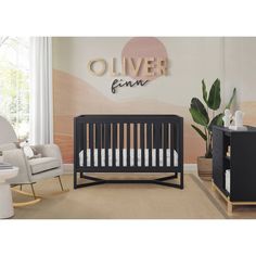 a baby's room with a crib, rocking chair and wall decal