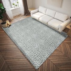 a white couch sitting on top of a hard wood floor next to a large rug