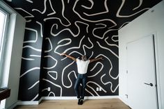 a man standing in front of a black wall with white lines painted on the walls