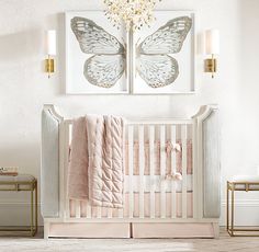 a baby's room with two butterfly paintings on the wall and a crib