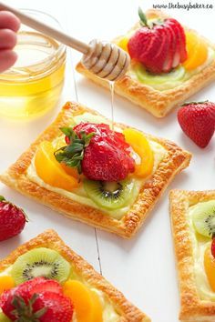 four pieces of bread with fruit on top and honey in the middle next to them