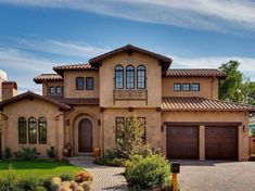 a large house with two car garages in the front yard and landscaping around it