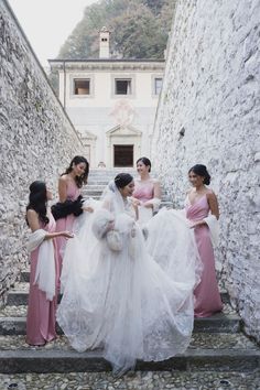 four bridesmaids in pink dresses standing on stairs