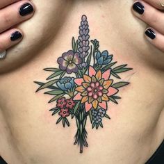 a woman's stomach with flowers and leaves tattooed on her chest, while holding her hands behind her back