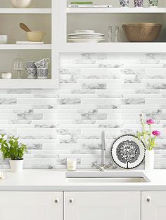 a kitchen with white cupboards and shelves filled with plates, bowls and vases