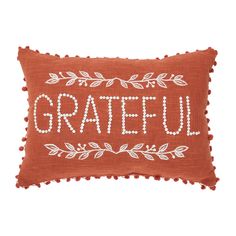 an orange pillow with the words grateful written on it, and leaves in white lettering