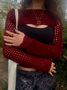 a woman with her arms crossed wearing a red knitted sweater