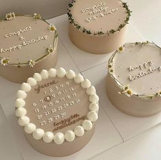 three decorated cakes sitting on top of a white counter next to each other with writing on them