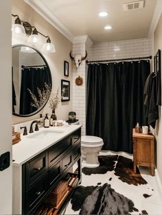 a white toilet sitting next to a black and white rug in a bathroom under a mirror