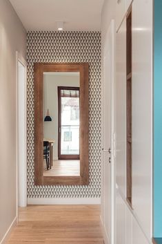 an empty hallway with a large mirror on the wall and wooden floors in front of it