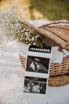 a basket with flowers and pictures on it sitting next to an empty photo album in front of some baby's breath