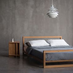 a bed sitting next to a night stand with two lamps hanging from it's sides