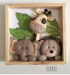 three stuffed animals in a wooden frame with leaves on the bottom and one is holding a green leaf